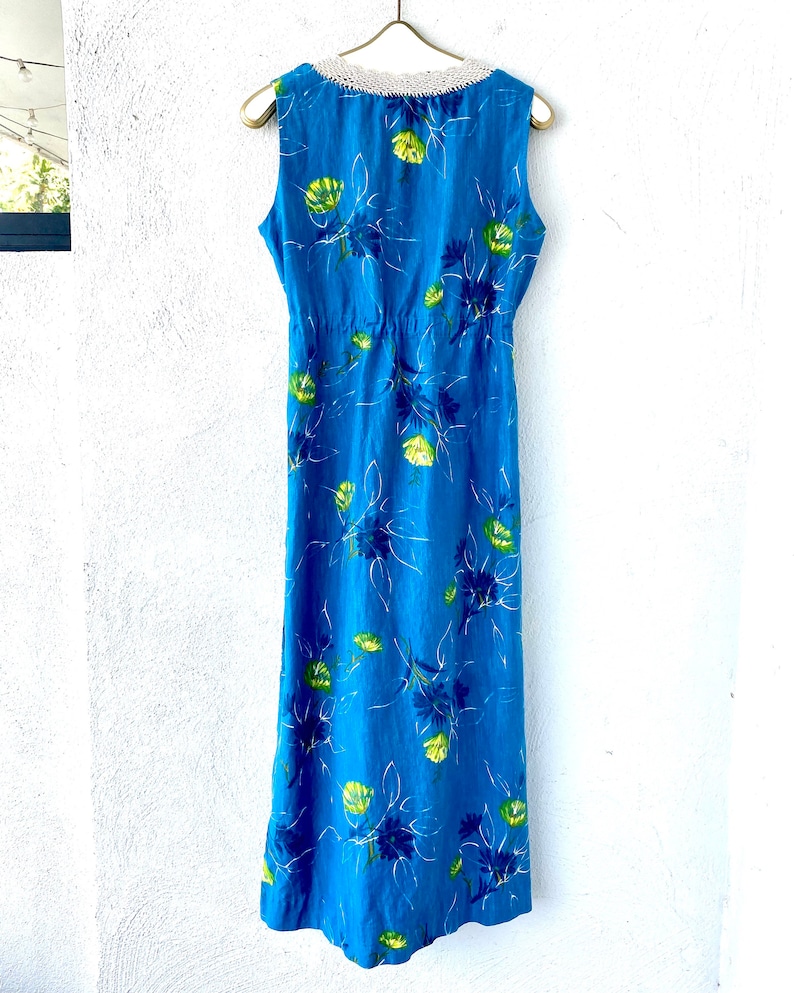 May include: A long blue sleeveless dress with a white crochet neckline and a floral print. The dress has a fitted bodice and a flowing skirt.