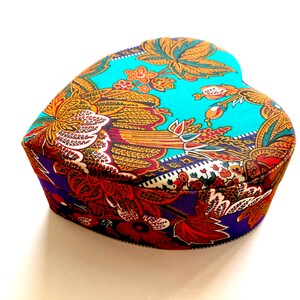May include: A heart-shaped box with a colorful floral pattern. The box is made of fabric and has a blue, purple, and orange color scheme.