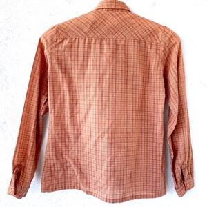 May include: A long-sleeved button-down shirt in a brown and white plaid pattern.