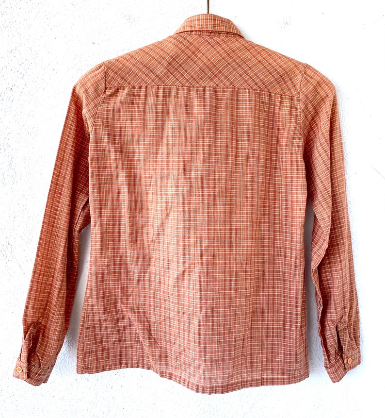 May include: A long-sleeved button-down shirt in a brown and white plaid pattern.
