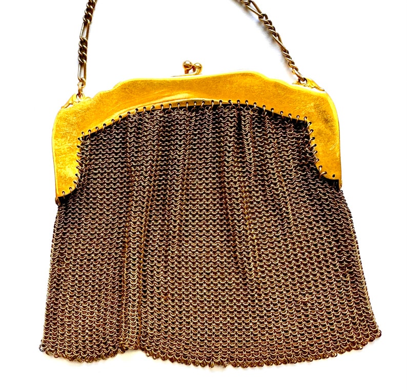 Pu&ograve; includere: Una borsa a rete dorata con una chiusura dorata e una tracolla a catena.