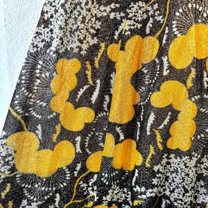 May include: Black sheer fabric with a yellow floral pattern. The fabric has a textured, almost sparkly appearance.