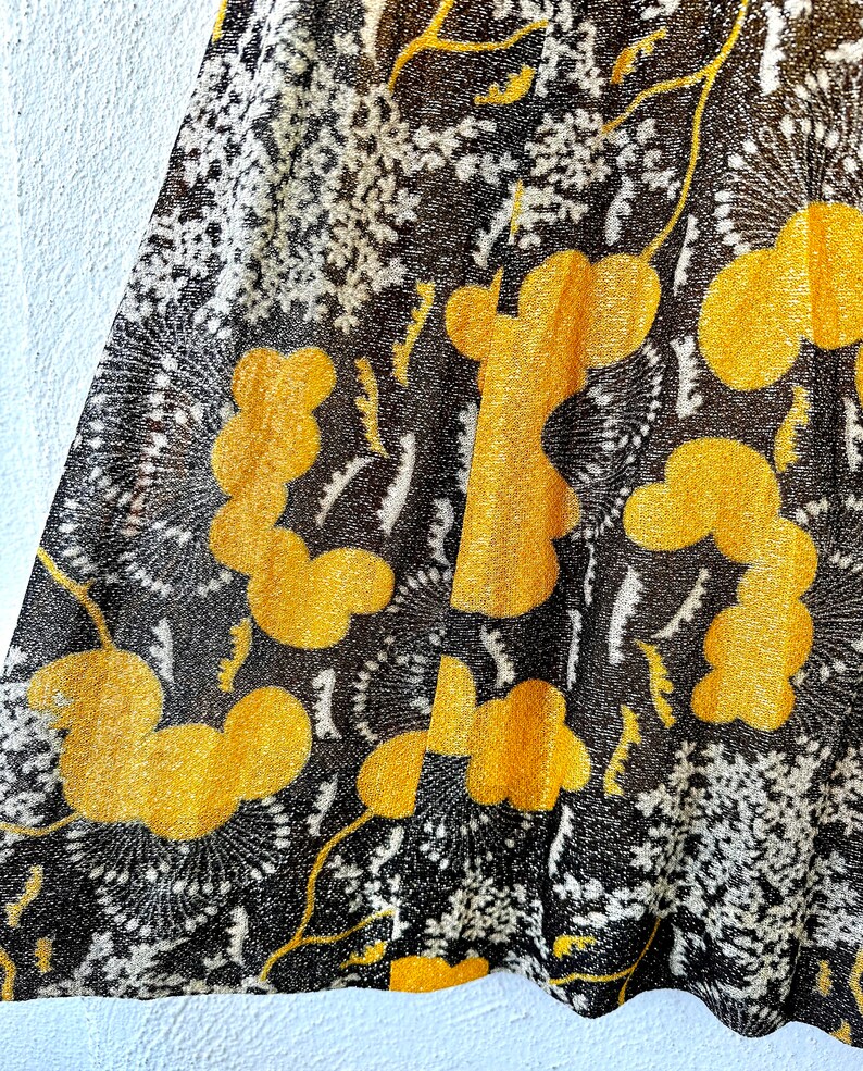 May include: Black sheer fabric with a yellow floral pattern. The fabric has a textured, almost sparkly appearance.