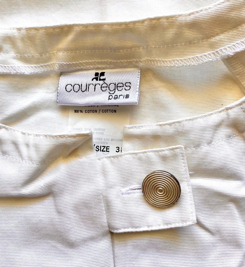 May include: White cotton pants with a Courr&egrave;ges Paris label and a gold button. The label says "100% Cotton / Cotton" and "Size 3".