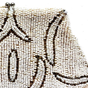 May include: A white beaded clutch bag with a floral design. The beads are small and closely spaced, creating a smooth, textured surface.