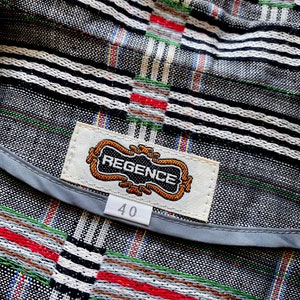 May include: A garment featuring a black, white, red, and green woven plaid pattern. A rectangular white fabric label is stitched to the interior, displaying the text REGENCE in black letters within a decorative gold border, with a size 40 tag below.