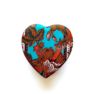 May include: A heart-shaped box with a blue background and a floral pattern in shades of brown, orange, and white.