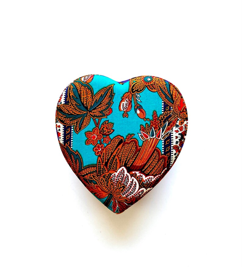 May include: A heart-shaped box with a blue background and a floral pattern in shades of brown, orange, and white.