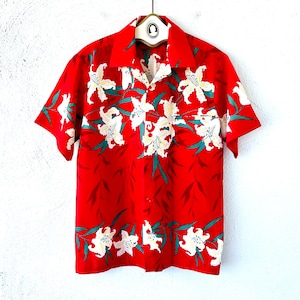 May include: A red short-sleeved button-up shirt with a white floral print. The shirt has a collar and a button-up front.