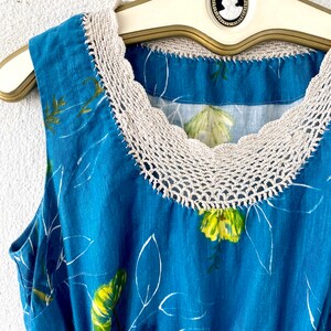 May include: A sleeveless blue dress with a white crochet neckline and a floral print. The dress has a fitted bodice and a flowing skirt.