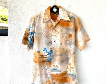 May include: A short-sleeved button-down shirt with a beige background and a colorful abstract print. The print features blue, orange, and white colors.