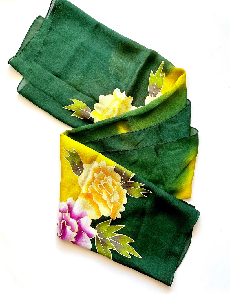 K&ouml;nnte beinhalten: Ein gr&uuml;ner und gelber Seidenschal mit Blumenmuster. Die Blumen sind gelb, rosa und lila.