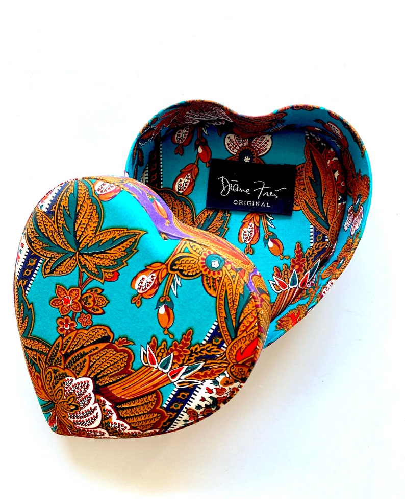 May include: A turquoise heart-shaped box with a paisley pattern and a label that reads "Diane Fries Original".