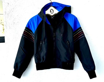 May include: A black and blue hooded jacket with a rainbow stripe detail on the sleeves. The jacket has a zipper closure and two pockets on the front.