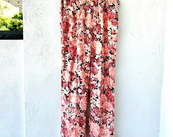 Könnte beinhalten: Weite Hose mit einem Blumendruck mit rosa und roten Blumen auf schwarzem Hintergrund.