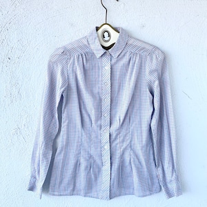 May include: A white button-down shirt with a blue and red plaid pattern. The shirt has a collared neckline and long sleeves.