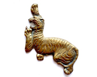 May include: A gold-colored metal tiger figurine with detailed stripes. The tiger is depicted in a leaping pose with its mouth open.