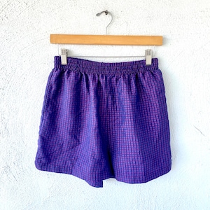 May include: Purple and pink checkered athletic shorts with an elastic waistband.