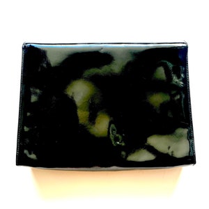 Op de afbeelding: Een zwarte clutch van patentleer.