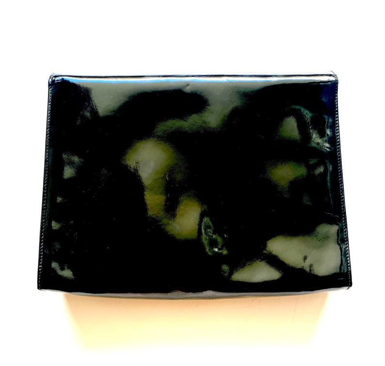 Op de afbeelding: Een zwarte clutch van patentleer.
