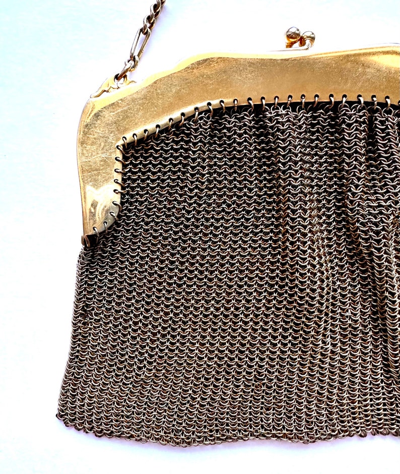 Pu&ograve; includere: Una borsa a rete di catena dorata con chiusura a scatto. La borsa &egrave; realizzata con piccoli anelli di metallo collegati.