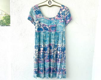 May include: A short-sleeved dress featuring a scoop neckline and a gathered waist. The fabric displays a repeating pattern of blue floral motifs and abstract geometric shapes in shades of light blue, white, and soft purple throughout the garment.