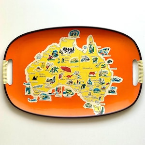 May include: Oval serving tray with a vibrant orange background and a yellow map of Australia. The map is detailed with illustrations of landmarks and icons. The tray has woven handles and a dark brown border.