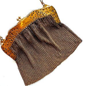 Pu&ograve; includere: Una borsa a catena dorata con una chiusura a filigrana e un corpo a rete.
