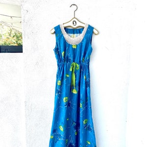 May include: A blue maxi dress with a white crochet neckline and green ribbon tie. The dress has a floral print with green leaves and white outlines.
