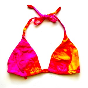 Puede incluir: Un top de bikini de color rosa y naranja con estampado tie-dye y tirantes ajustables.