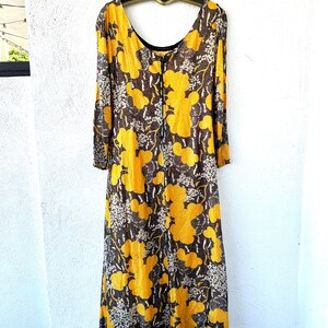 May include: A long, yellow and brown floral print dress with a scoop neck and long sleeves. The dress has a zipper closure in the back.
