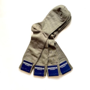 May include: Four pairs of green socks with a subtle pattern. Each sock has a blue label with the text "MONSIEUR GIVENCHY" on it.