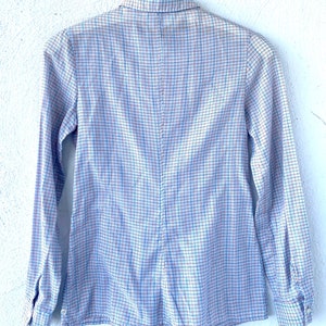 May include: A long-sleeved button-down shirt with a blue, white, and red plaid pattern.