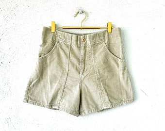 May include: Beige corduroy shorts with a high waist and side pockets. The shorts have a straight leg and a relaxed fit.