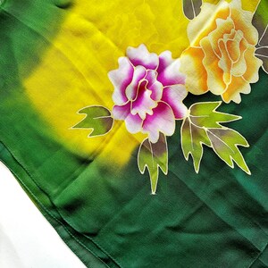 K&ouml;nnte beinhalten: Ein gr&uuml;ner Seidenschal mit einem gelben, rosa und orangenen Blumendesign. Der Schal hat einen Farbverlauf von gr&uuml;n zu gelb im Hintergrund.