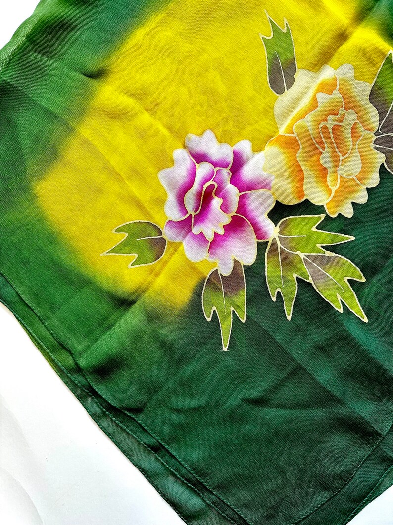 K&ouml;nnte beinhalten: Ein gr&uuml;ner Seidenschal mit einem gelben, rosa und orangenen Blumendesign. Der Schal hat einen Farbverlauf von gr&uuml;n zu gelb im Hintergrund.