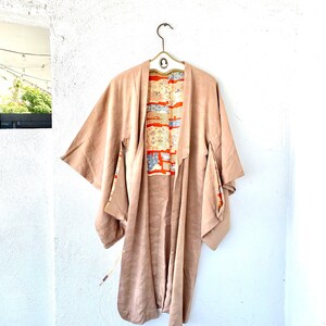 May include: A long, brown kimono with a patterned lining. The kimono has wide sleeves and a tie at the waist.