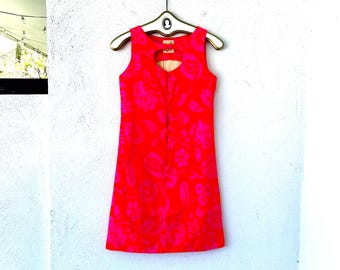 Vestido mini hawaiano vintage de los años 60, color rosa neón con estampado floral y aberturas.