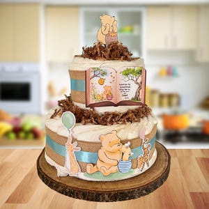 May include: A two-tiered diaper cake with Winnie the Pooh characters. The cake has a rustic burlap and blue ribbon design, with a Winnie the Pooh book and characters. The top tier features a Winnie the Pooh figurine holding a honey pot.