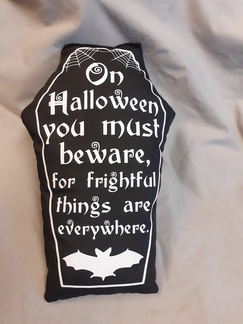 May include: Black and white Halloween pillow shaped like a coffin with the text "On Halloween you must beware, for frightful things are everywhere." and a white bat silhouette.