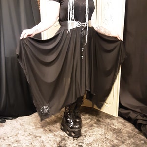 May include: A black maxi skirt with a high waist and a flowing, asymmetrical hemline. The skirt is made of a lightweight, sheer fabric and features a silver belt with a decorative buckle.