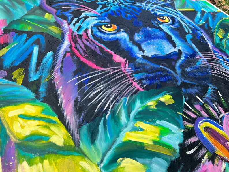 May include: A close-up of a black panther's face with bright blue and yellow eyes. The panther is surrounded by vibrant green, yellow, and blue tropical leaves.