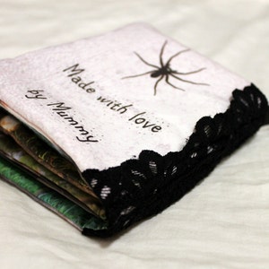 May include: A handmade book with a white cover and black lace trim. The cover has the text "Made with love by Mummy" and a black spider illustration.