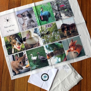 May include: A white fabric with a collage of images of animals and insects. The fabric has the text "Made with love by Mummy" and "Beasts & Bugs" printed on it.