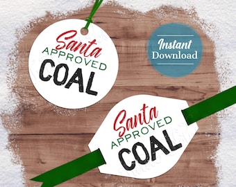 May include: Two white round gift tags with red and black text that says "Santa Approved Coal". The tags are on a wood background with white snow on the edges. One tag has a green ribbon attached.
