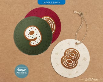 Op de afbeelding: Drie ronde cadeaulabels van 8,9 cm. Eén label is donkergroen met een wit glazuur cijfer negen, één is donkerrood en één is wit met een bruin peperkoek cijfer acht en sneeuwvlokpatronen, voorzien van een touwtje van jute.