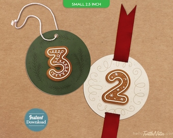 Op de afbeelding: Twee ronde cadeaukaartjes van 6,35 cm met cijfers in peperkoekstijl. Het groene kaartje toont het cijfer 3 met witte glazuurdetails en een wit touwtje. Het witte kaartje toont het cijfer 2 met witte glazuurdetails en een rood lint.