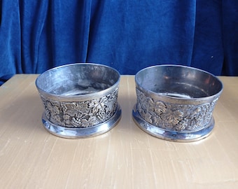 Paar zilverkleurige wijnstandaards met druiven op wijnstok.