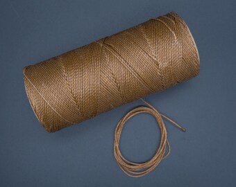 May include: A spool of brown twine with a small length of twine coiled next to it on a blue background.