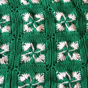 May include: Green and white crocheted blanket with a repeating pattern of four-leaf clover motifs.